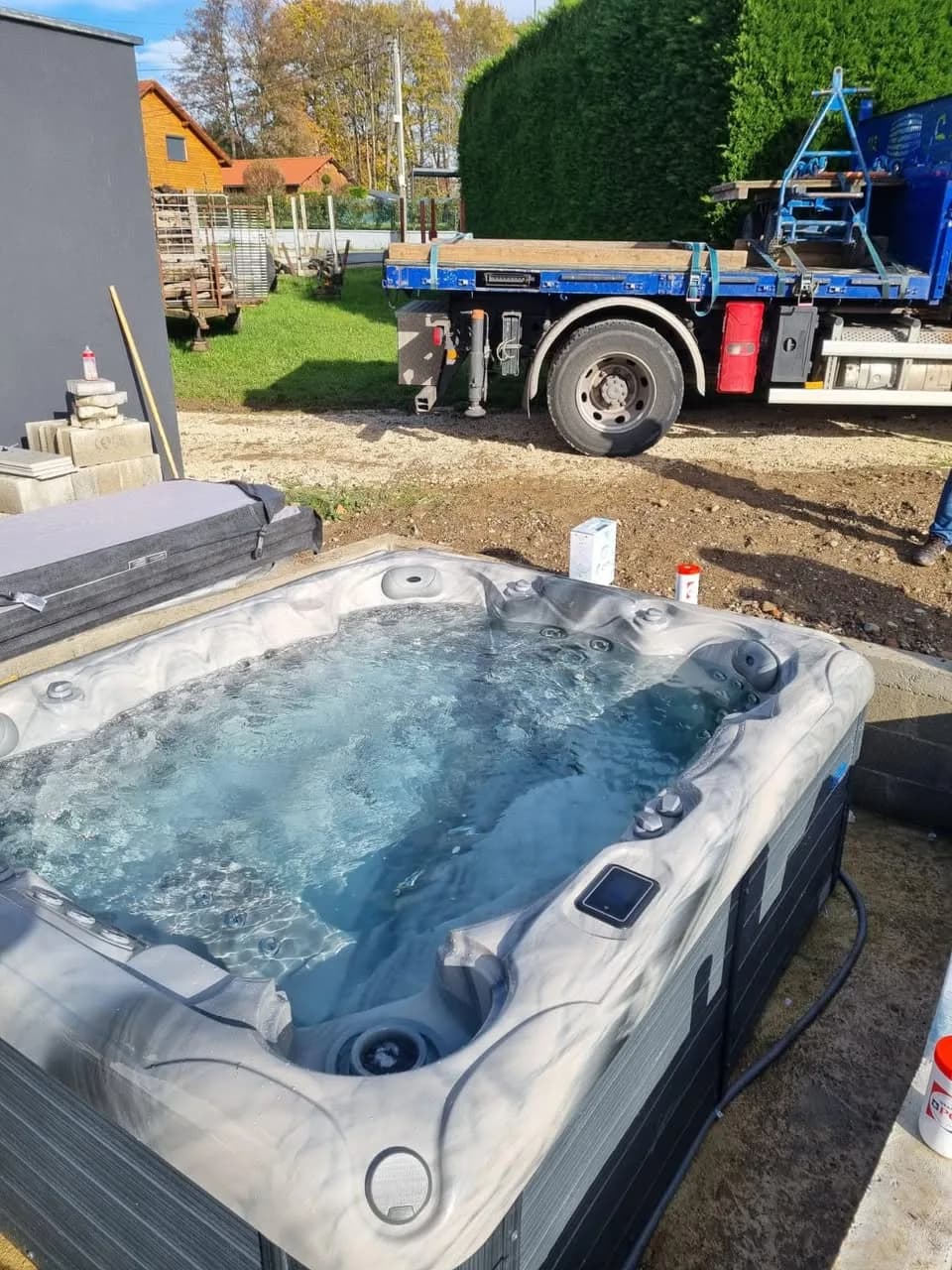 Installation d'un spa Emerald à Magny, dans un jardin, camion-grue à l'arrière
