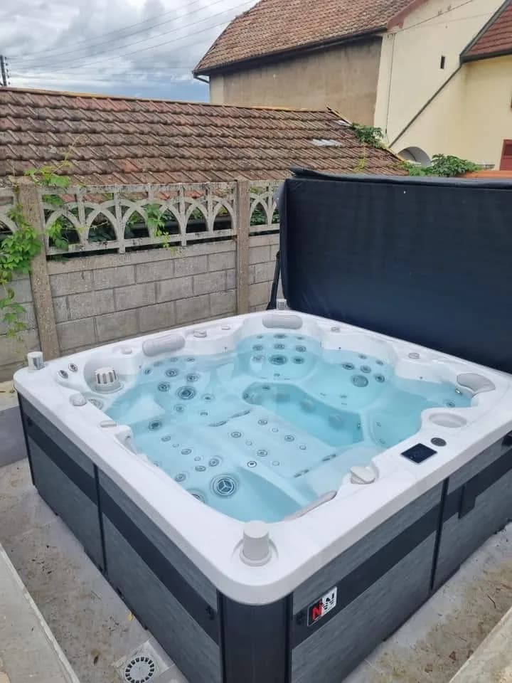 Installation d'un spa Hølen à Dampierre-sur-le-Doubs, sur une dalle devant un muret