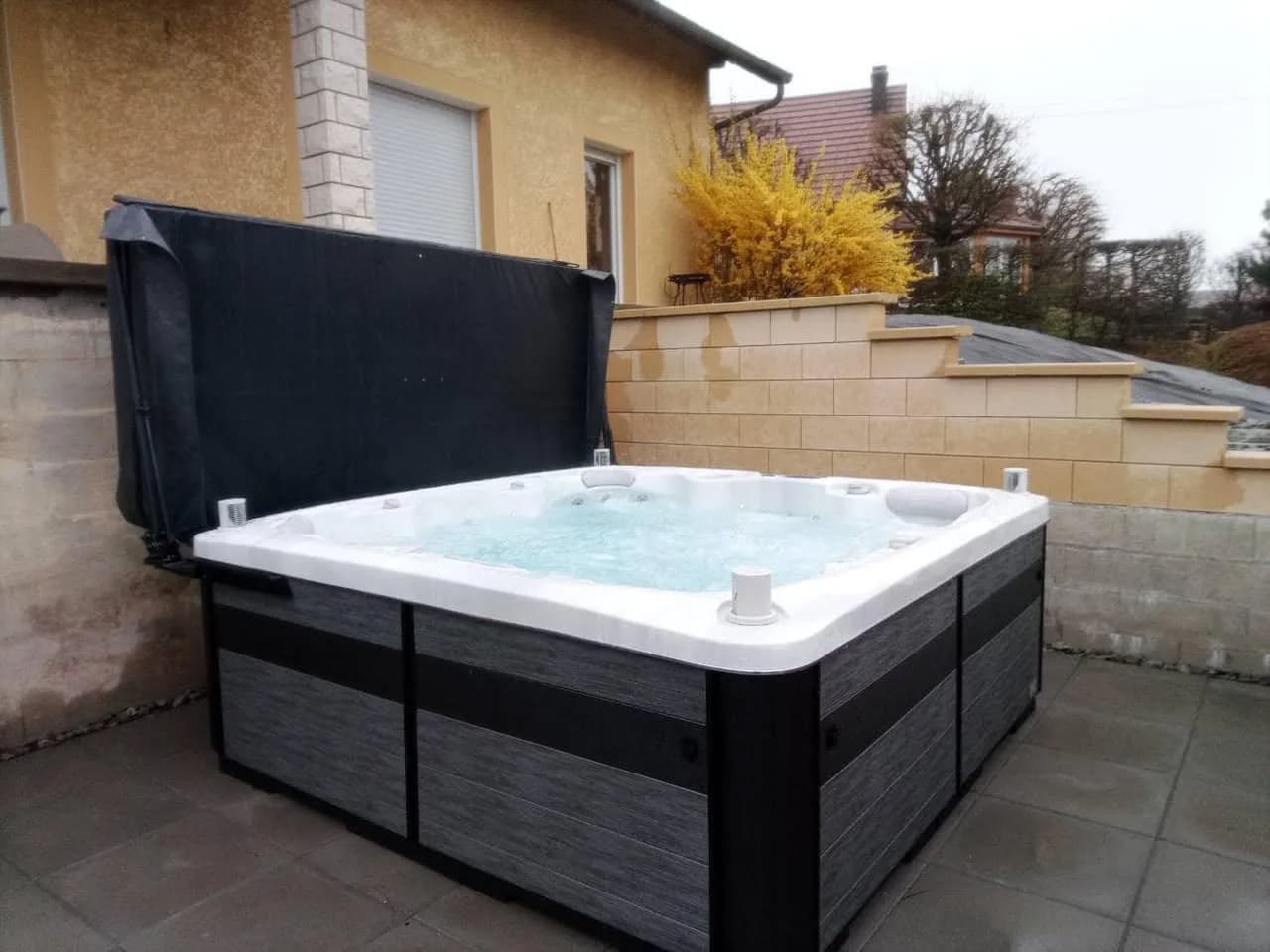 Installation d'un spa Hølen Full option à Abbévillers, sur une terrasse dallée, lève-couverture