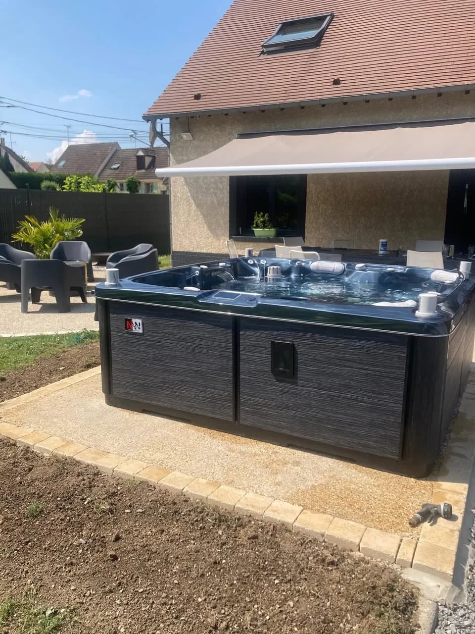 Installation d'un spa Hølen Full option à Goincourt, sur une dalle bordée de gravier