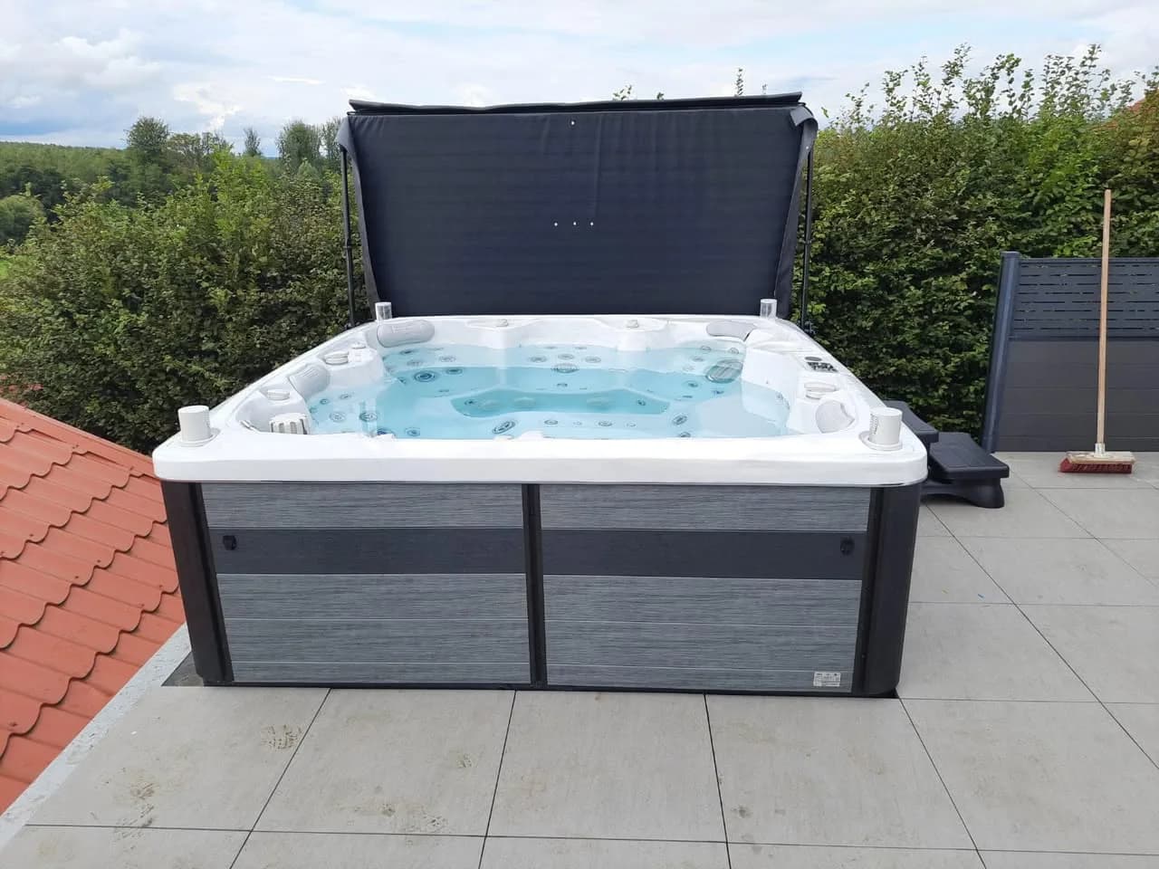 Installation d'un spa Hølen Full option à Hartzviller, sur une terrasse carrelée, lève-couverture