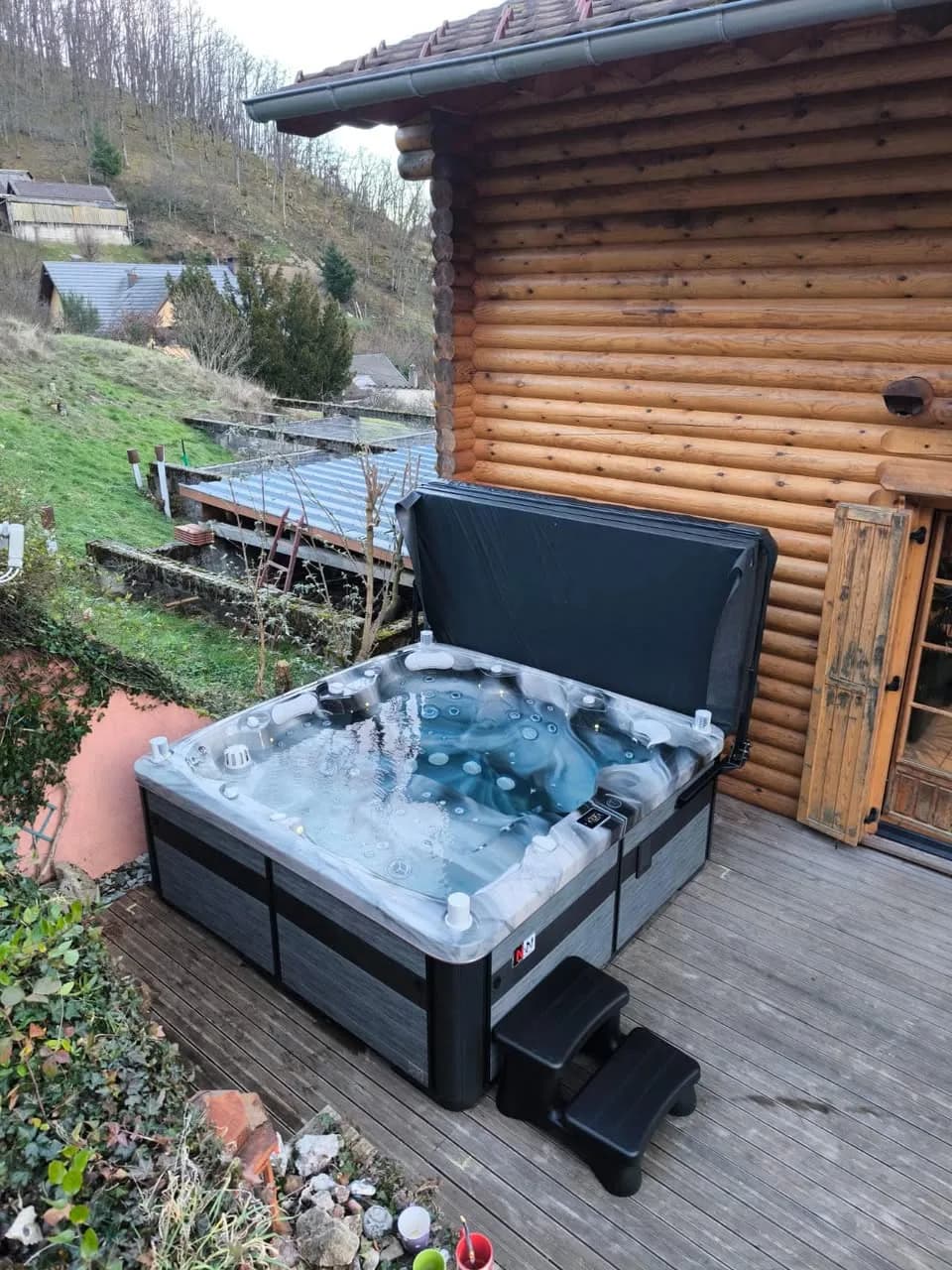 Installation d'un spa Hølen à Rimbach, sur une terrasse en bois contre un chalet