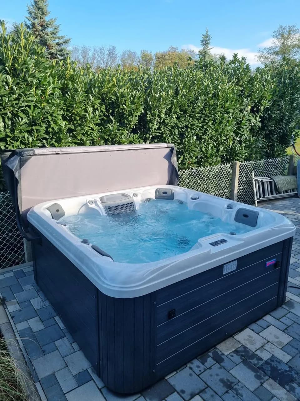 Installation d'un spa Hydro à Chalampé, sur des pavés au pied d'une haie