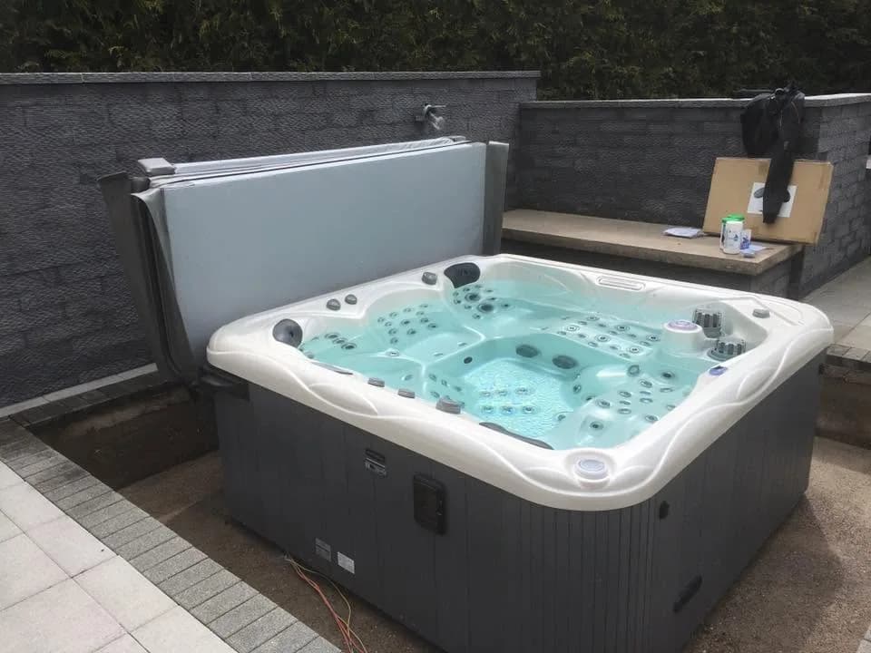Installation d'un spa Ipsilon Full option à Montbouton, sur une terrasse dallée, lève-couverture