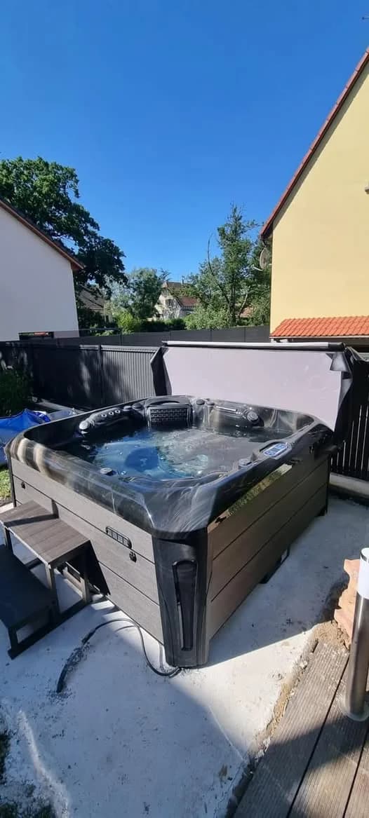 Installation d'un spa Kenya Full option à Richwiller, contre une palissade grise