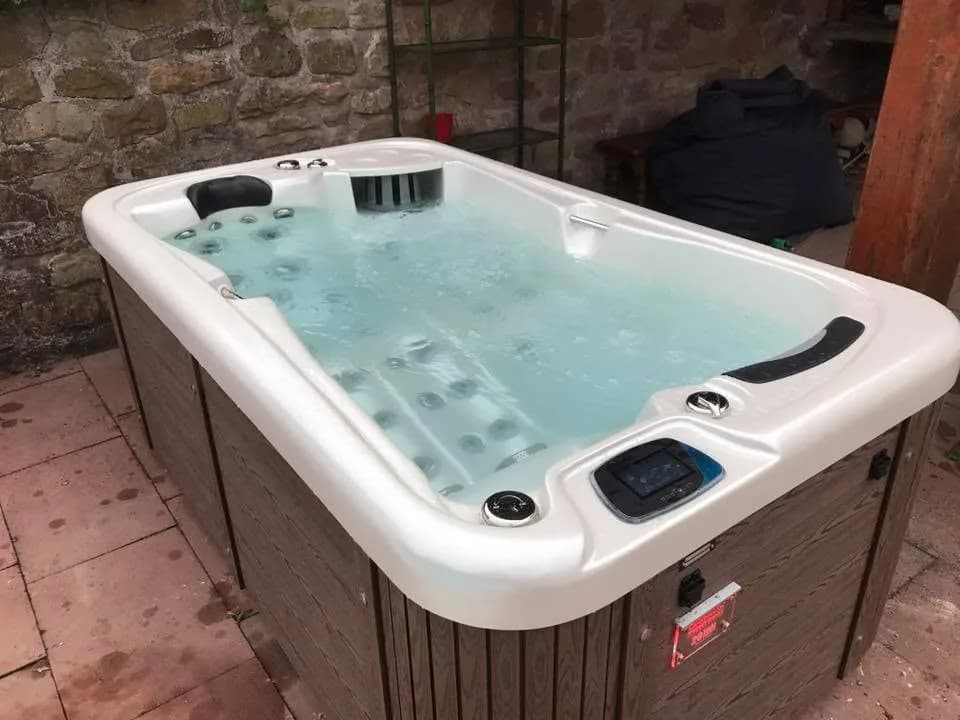 Installation d'un spa Lara mini New à Dieffenbach-au-Val, sur un dallage contre un mur en pierre