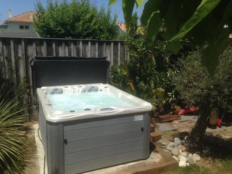 Installation d'un spa Montana à Arcachon, dans un jardin planté contre une palissade en bois