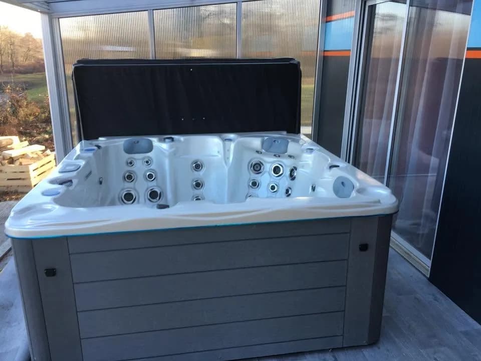 Installation d'un spa Montana à Burnhaupt-le-Haut, contre des parois vitrées, couverture relevée
