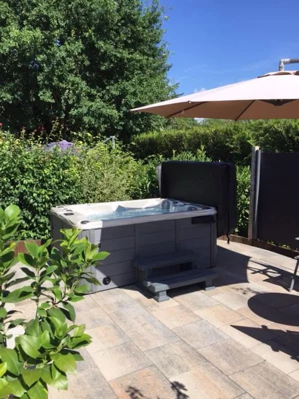 Installation d'un spa Montana Full option à Chalampé, sur une terrasse dallée dans un jardin fleuri