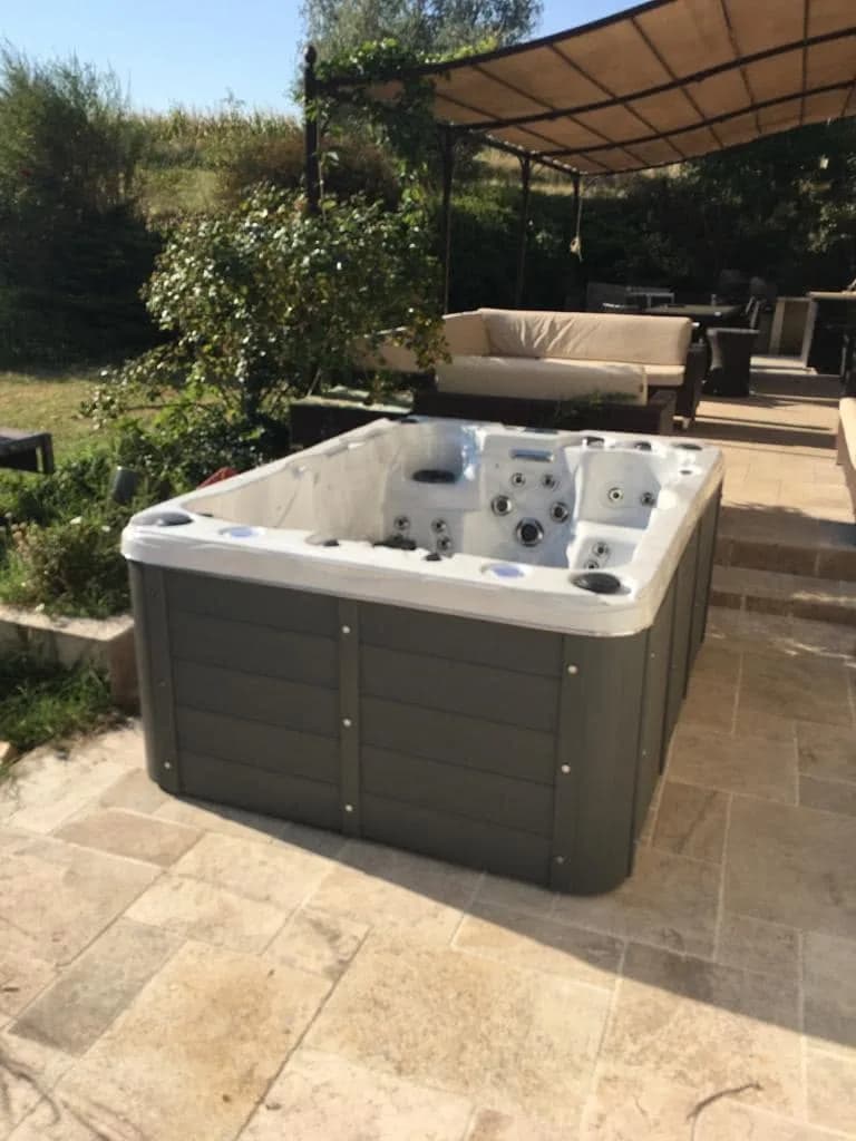 Installation d'un spa Montana Full option à Chatuzange-le-Goubet, sur un dallage en pierre près d'un mur en pierre