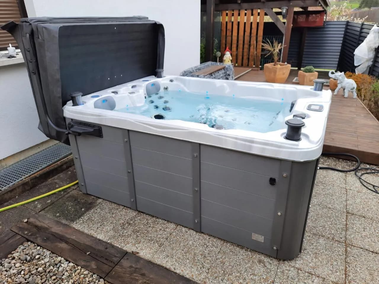 Installation d'un spa Montana Full option à Durlinsdorf, à côté d'une terrasse en bois, lève-couverture