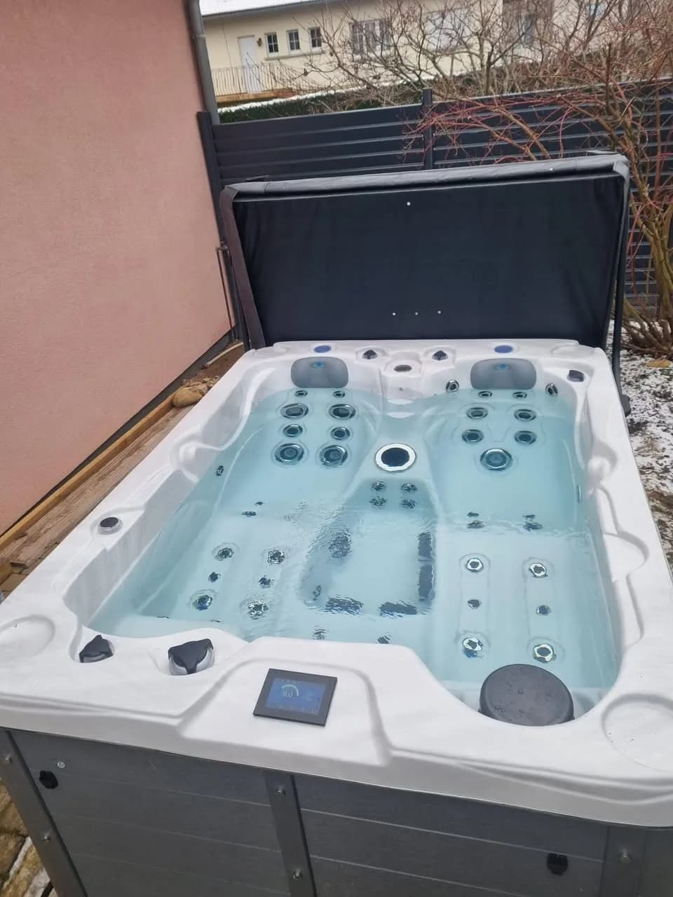 Installation d'un spa Montana à Hirtzbach, contre un mur crépi, lève-couverture