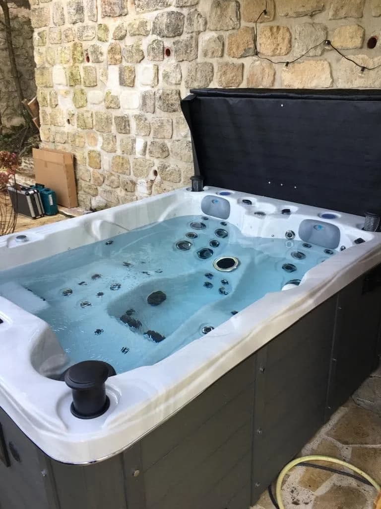 Installation d'un spa Montana à Nesles-la-Vallée, contre un mur en pierre