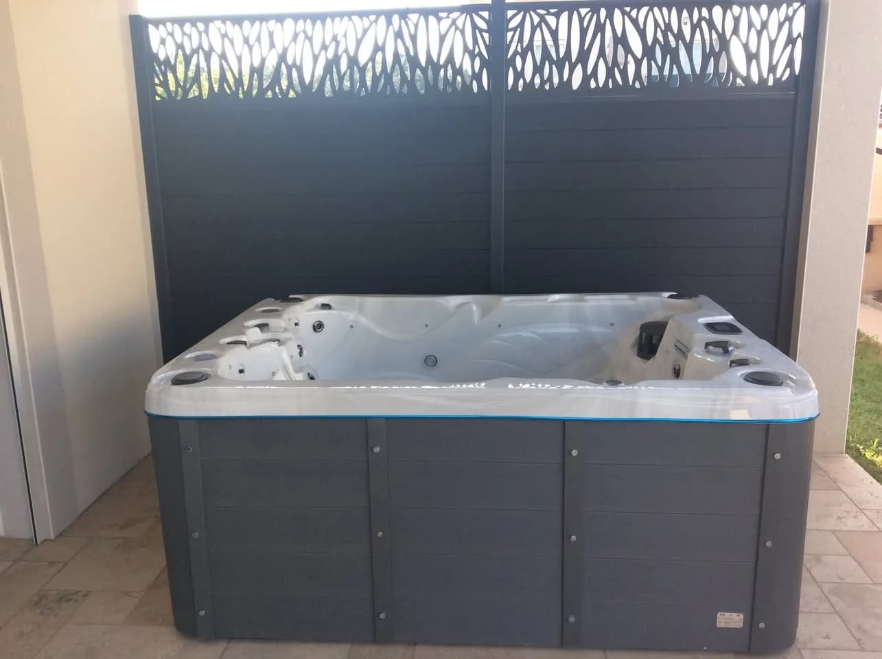 Installation d'un spa Montana à Portes-lès-Valence, sur une terrasse carrelée devant un panneau décoratif
