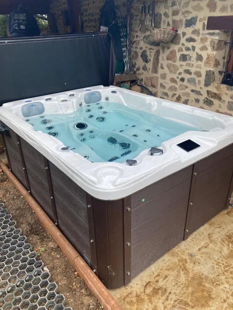 Installation d'un spa Montana à Saint-Clément-sur-Valsonne, contre un mur en pierre, tablier brun