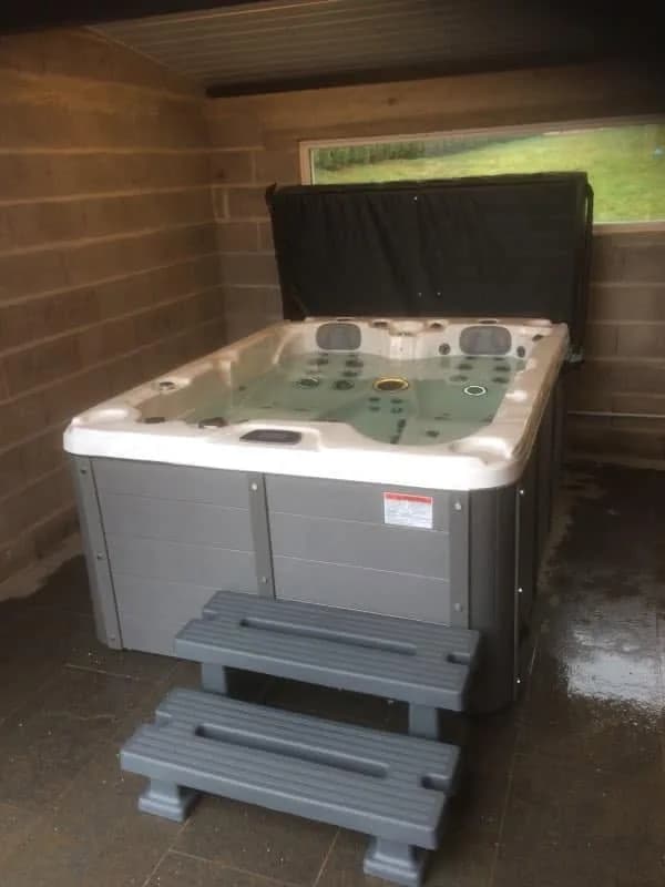 Installation d'un spa Montana à Saint-Dié-des-Vosges, sous un abri en bois, avec marchepied
