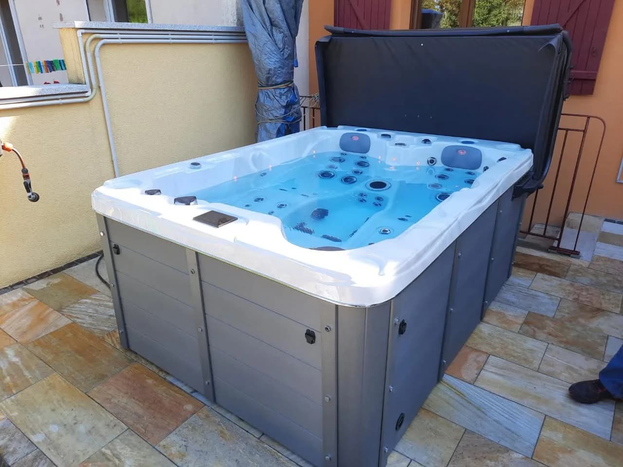 Installation d'un spa Montana à Saint-Louis, sur un dallage en pierre, lève-couverture