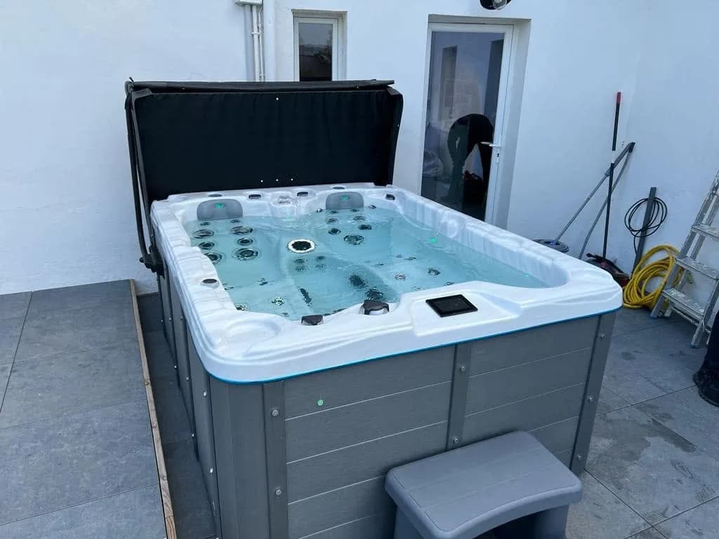 Installation d'un spa Montana à Saint-Nic, sur une dalle contre une maison blanche