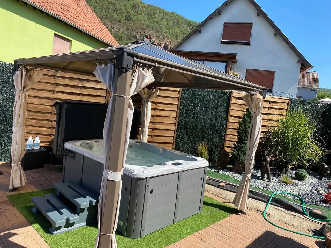 Installation d'un spa Montana, sous une tonnelle, sur du gazon synthétique