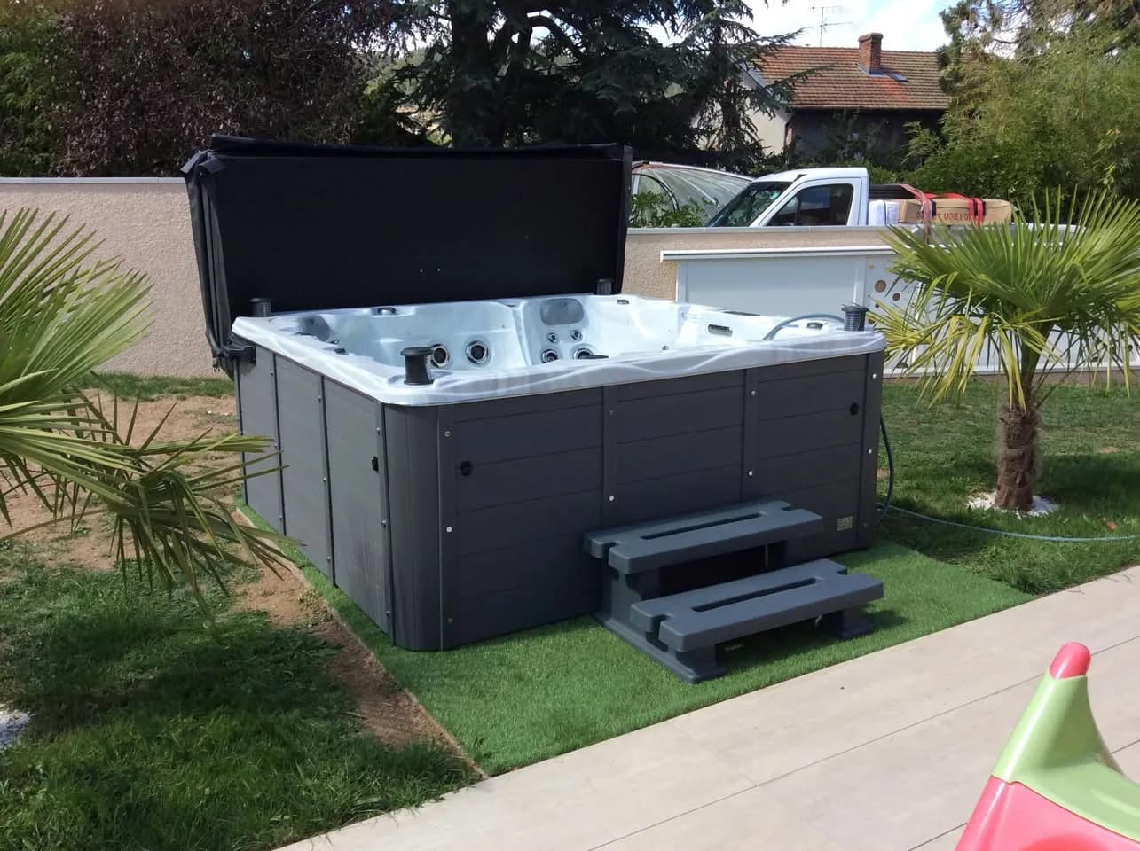 Installation d'un spa Montréal Full option à Aurec-sur-Loire, sur du gazon synthétique, avec lève-couverture