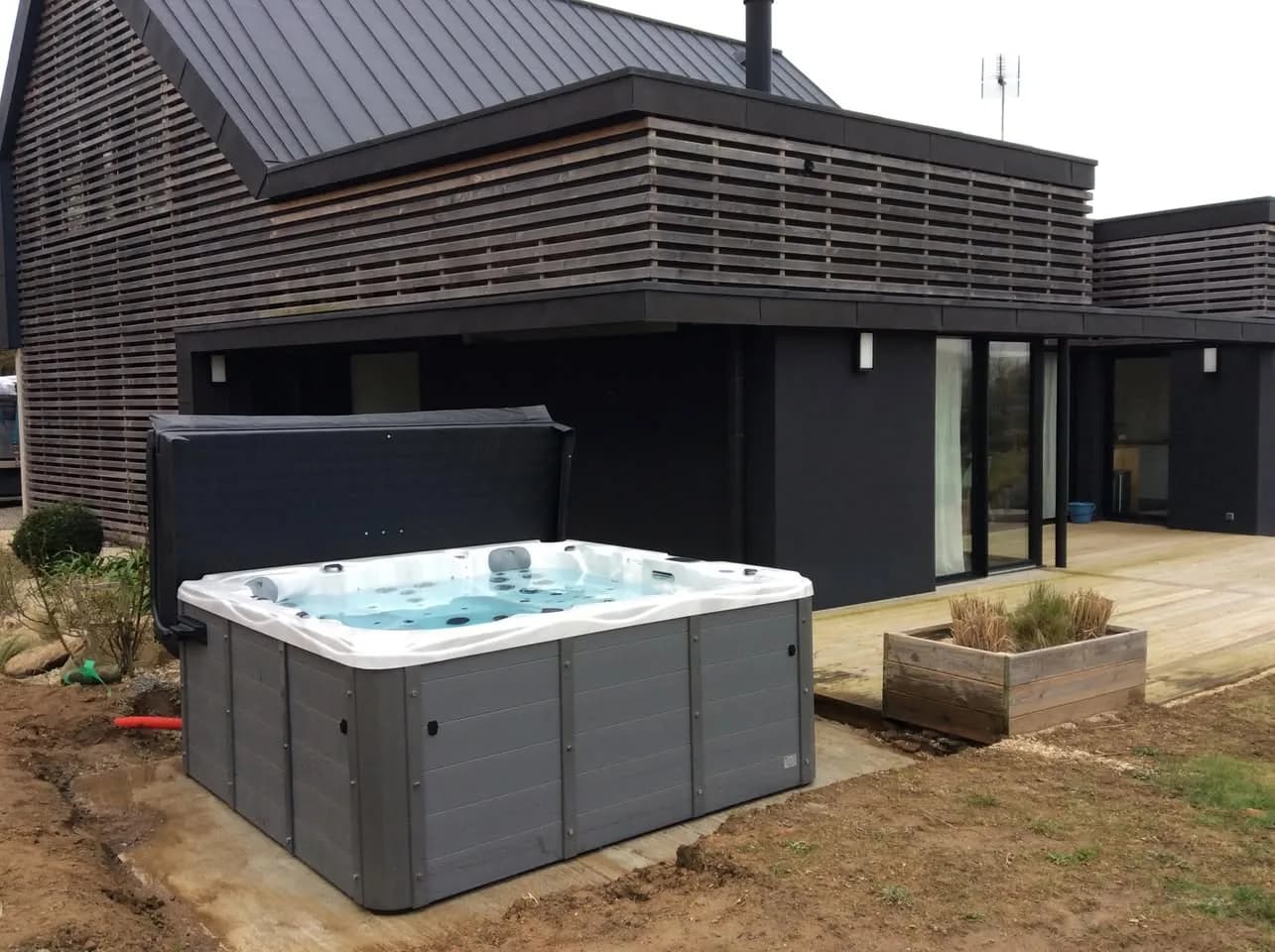 Installation d'un spa Montréal Full option à Perros-Guirec, au pied d'une terrasse en bois, lève-couverture