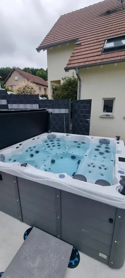 Installation d'un spa Montréal à Littenheim, sur une dalle devant une palissade grise