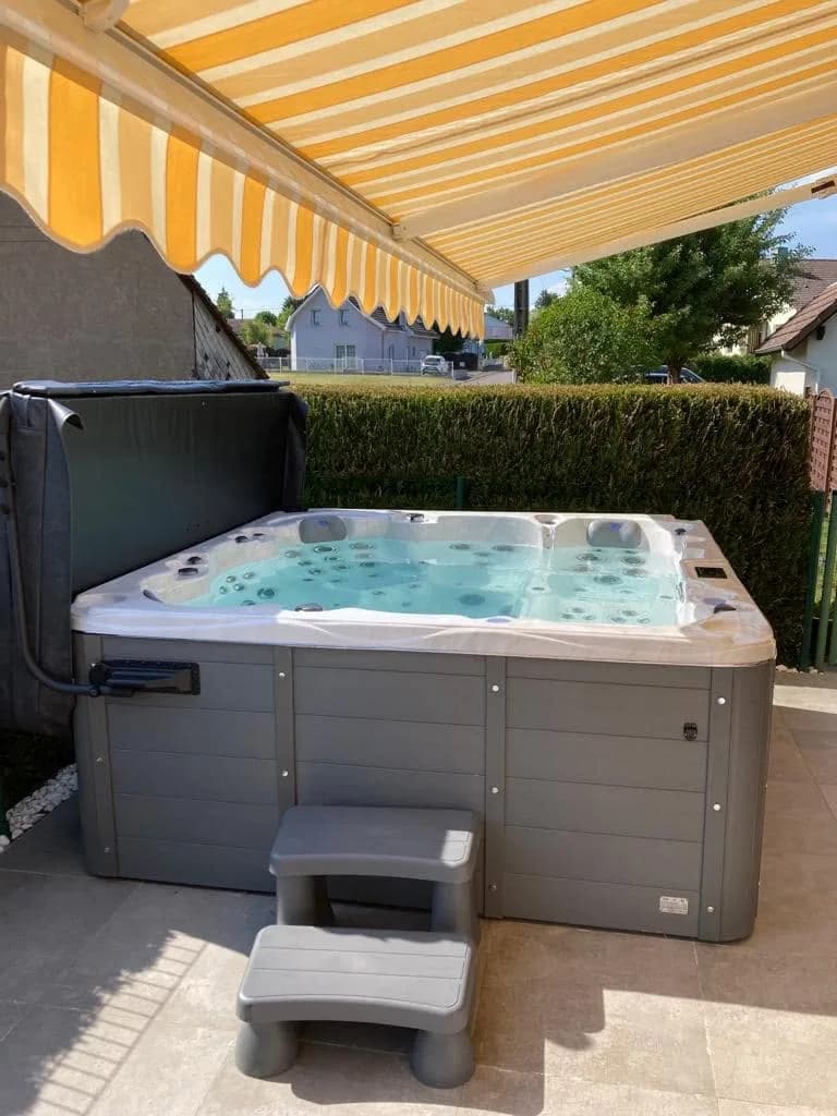 Installation d'un spa Montréal à Montreux-Château, sur une terrasse dallée sous un store banne