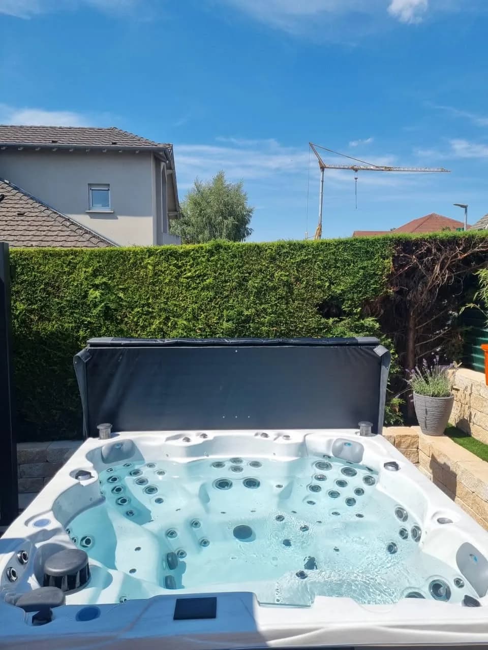 Installation d'un spa Montréal à Sarrebourg, sur une terrasse fleurie, couverture relevée