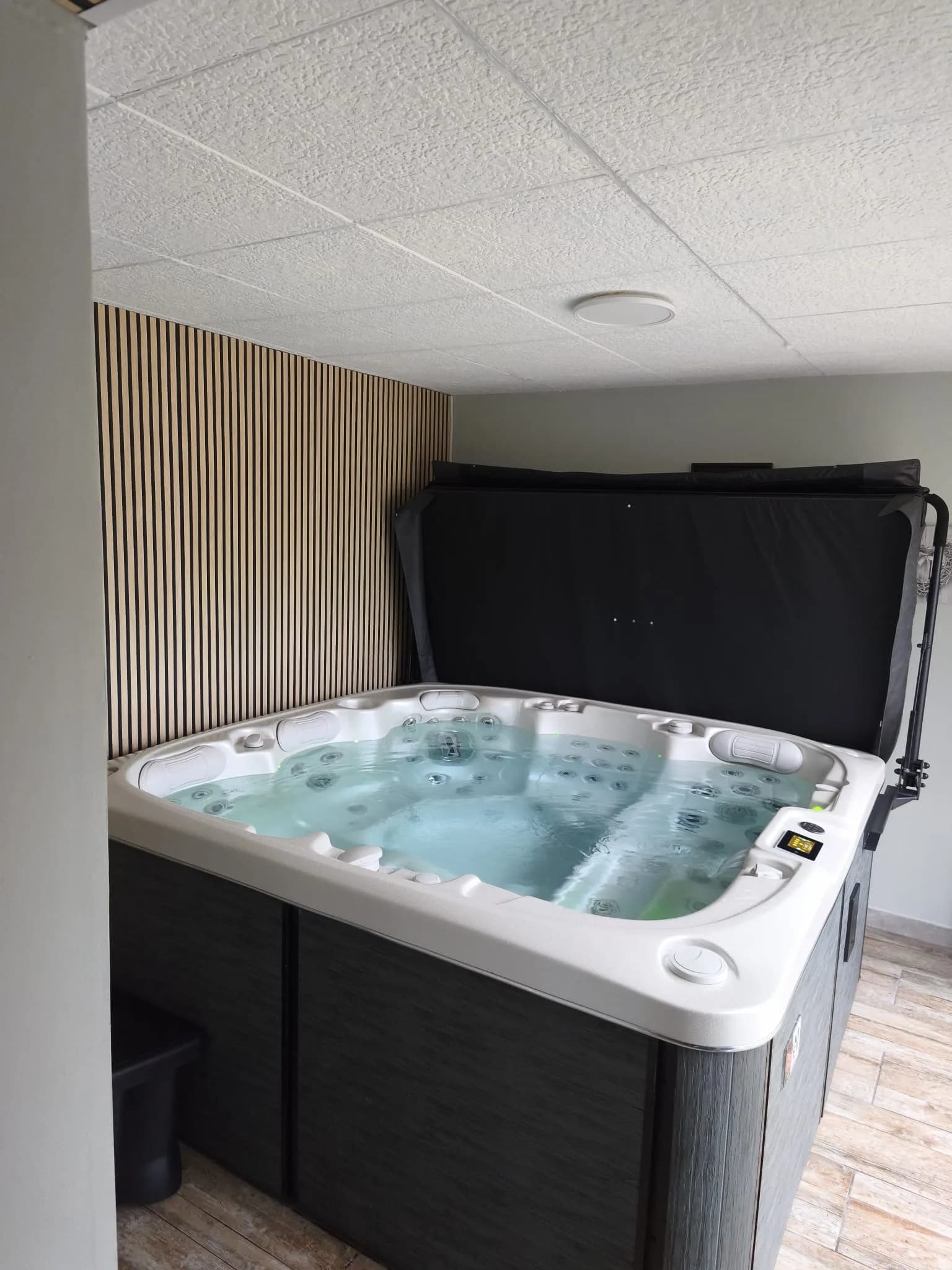 Installation d'un spa Øppland à Belfahy, en intérieur, devant un mur en tasseaux de bois