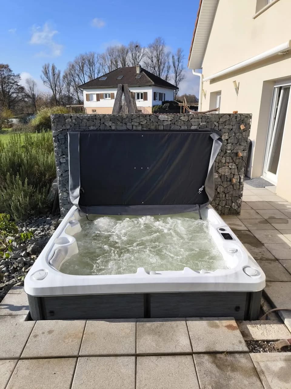 Installation d'un spa Øppland à Faulquemont, sur une terrasse dallée devant un mur en gabions