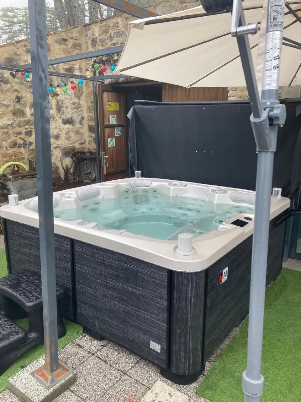 Installation d'un spa Øppland Full option à Chateau Serigues, sur un gazon synthétique devant une maison en pierre