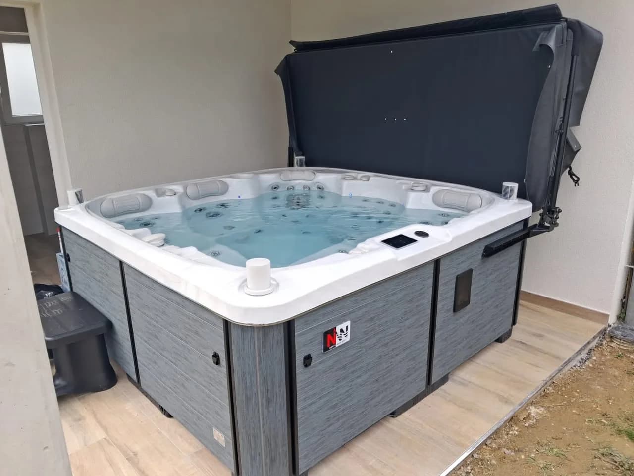 Installation d'un spa Øppland Full option, sous un abri contre un mur blanc