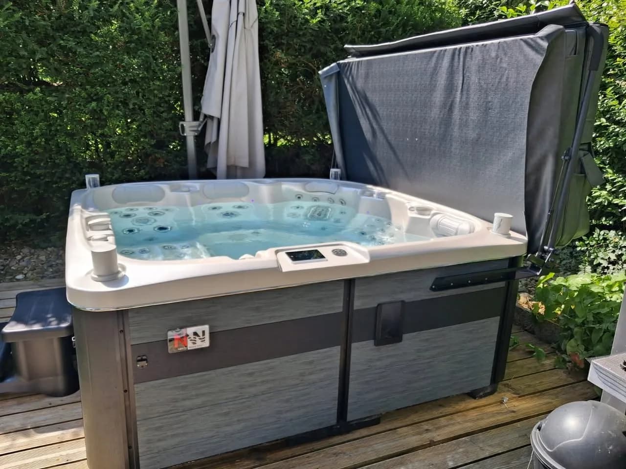 Installation d'un spa Øppland à Riedisheim, sur une terrasse en bois devant une haie