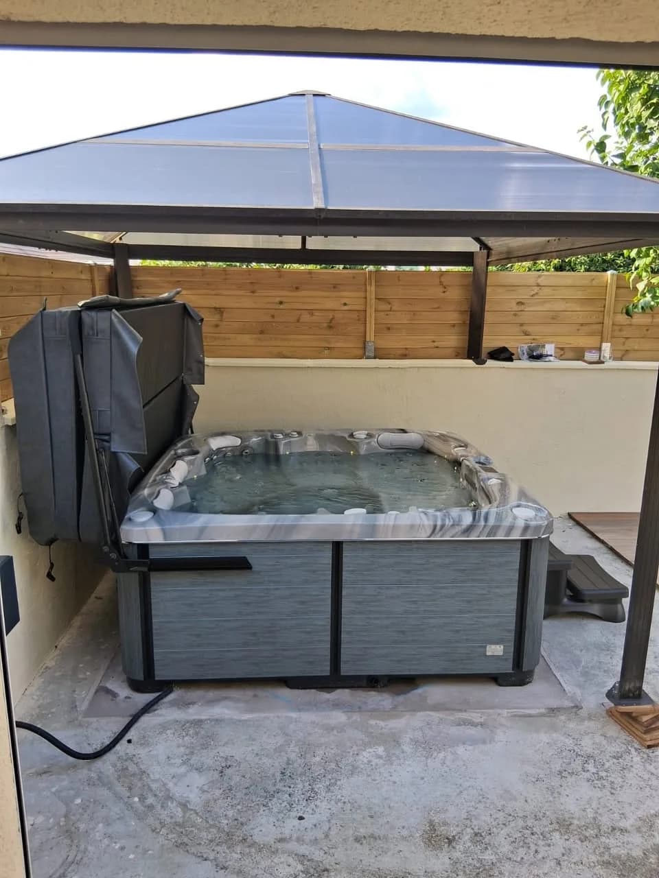 Installation d'un spa Øppland à Saint-Thibault-des-Vignes, sous une tonnelle à toit translucide