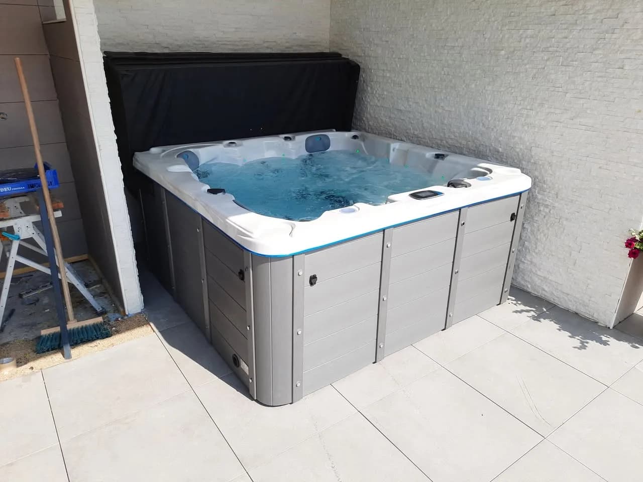 Installation d'un spa Ottawa à Charmois, sur une terrasse carrelée contre un mur blanc