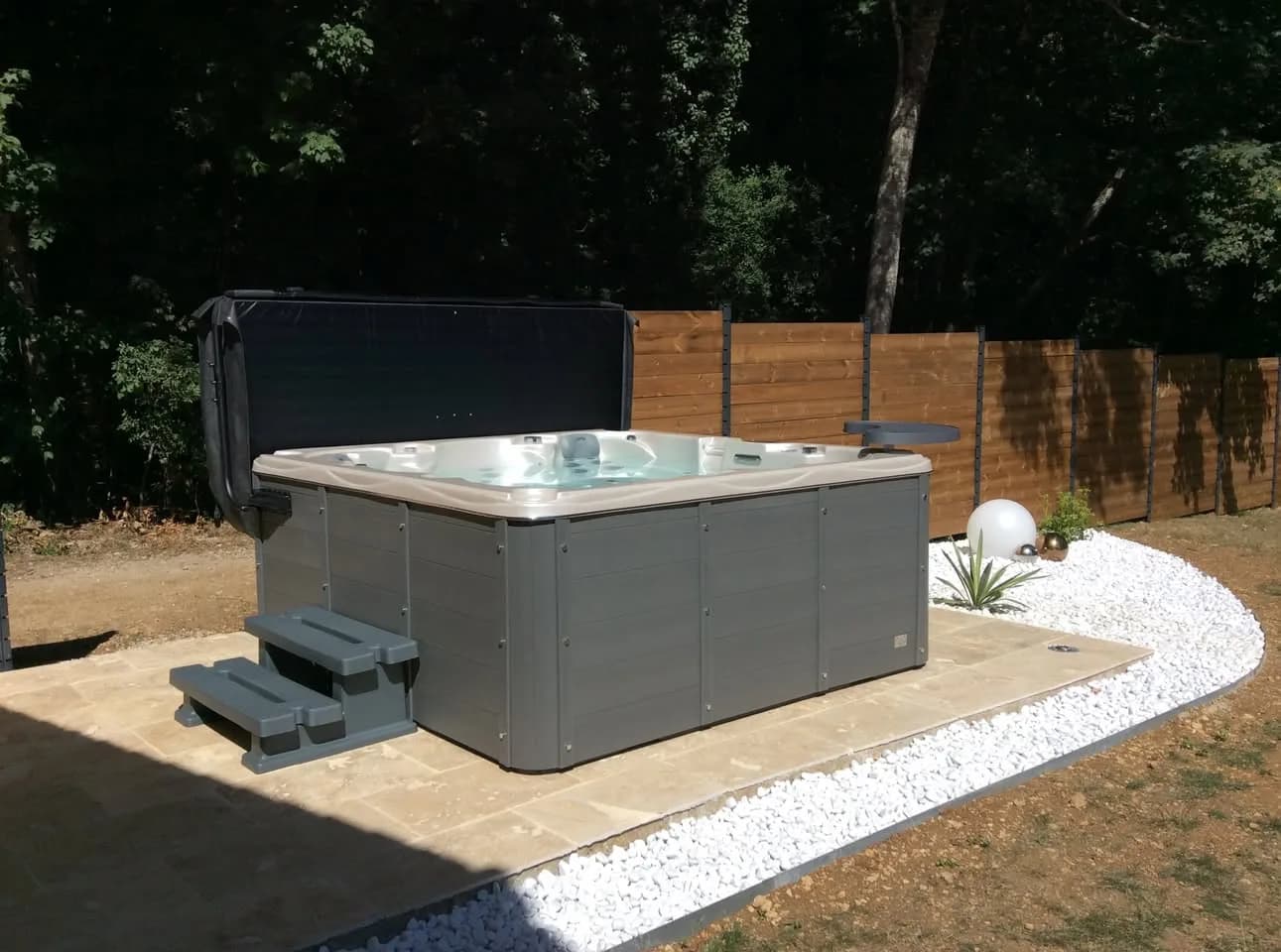 Installation d'un spa Ottawa à Châteauneuf, sur une dalle bordée de galets, avec marchepied