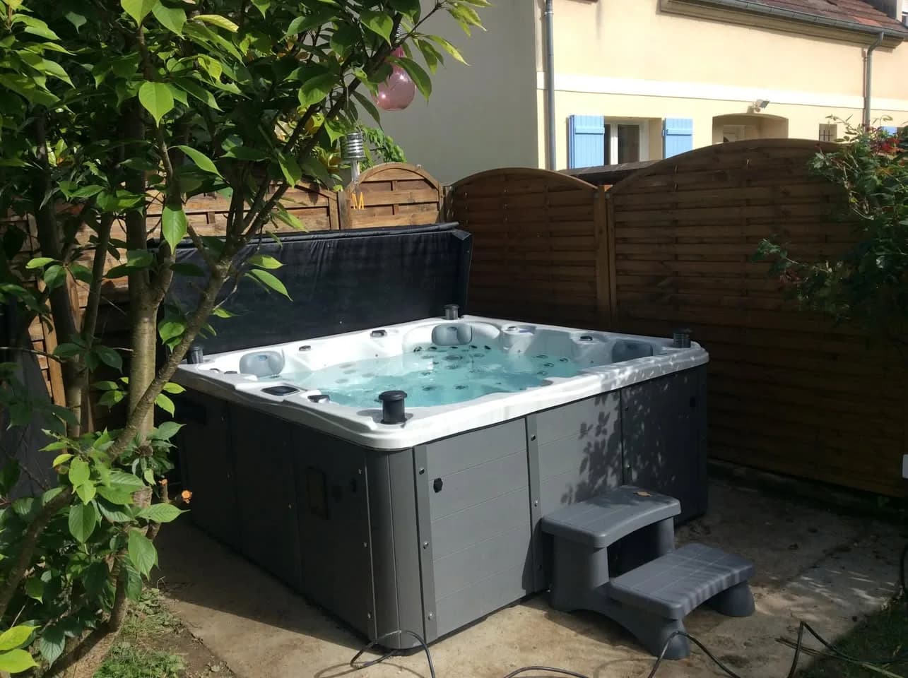 Installation d'un spa Ottawa Full option à Courcelles, devant une palissade en bois, marchepied