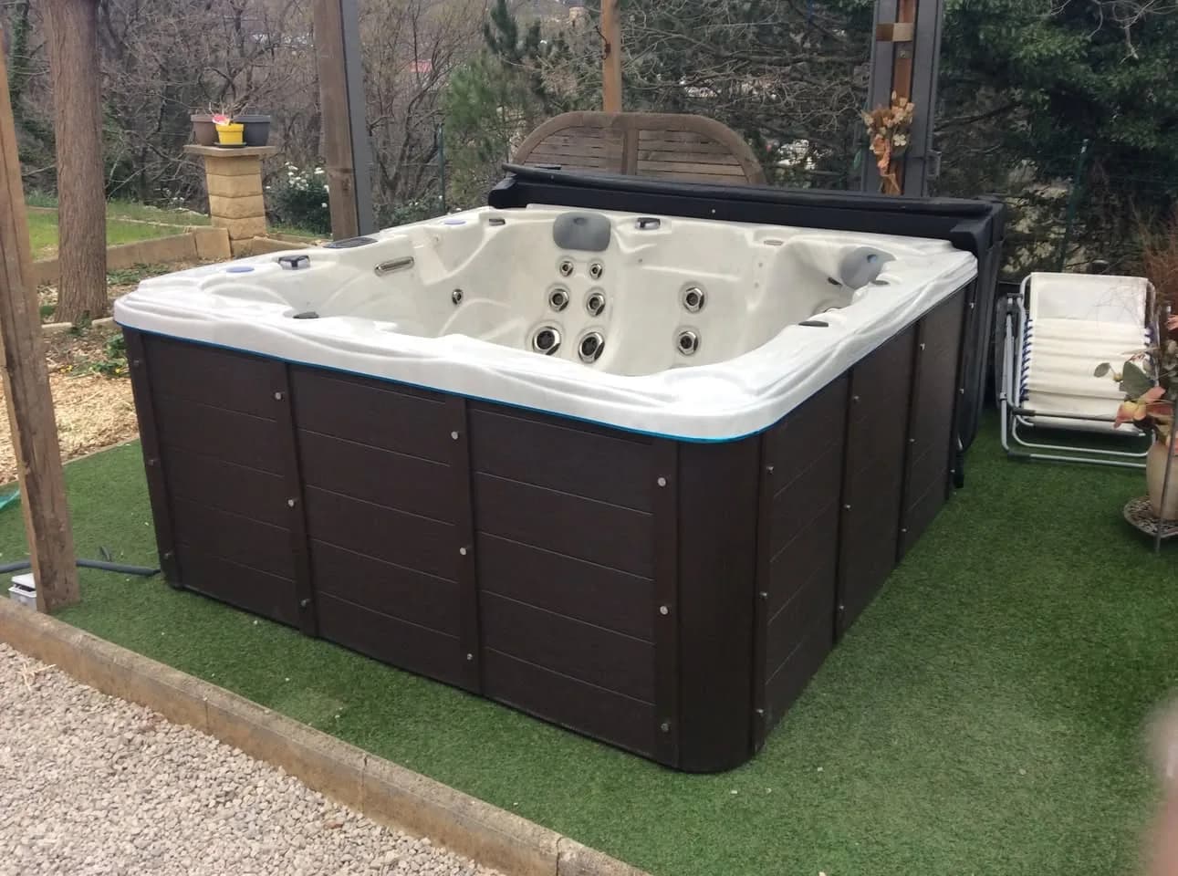 Installation d'un spa Ottawa à Poujols, sous une pergola en bois, sur une pelouse synthétique