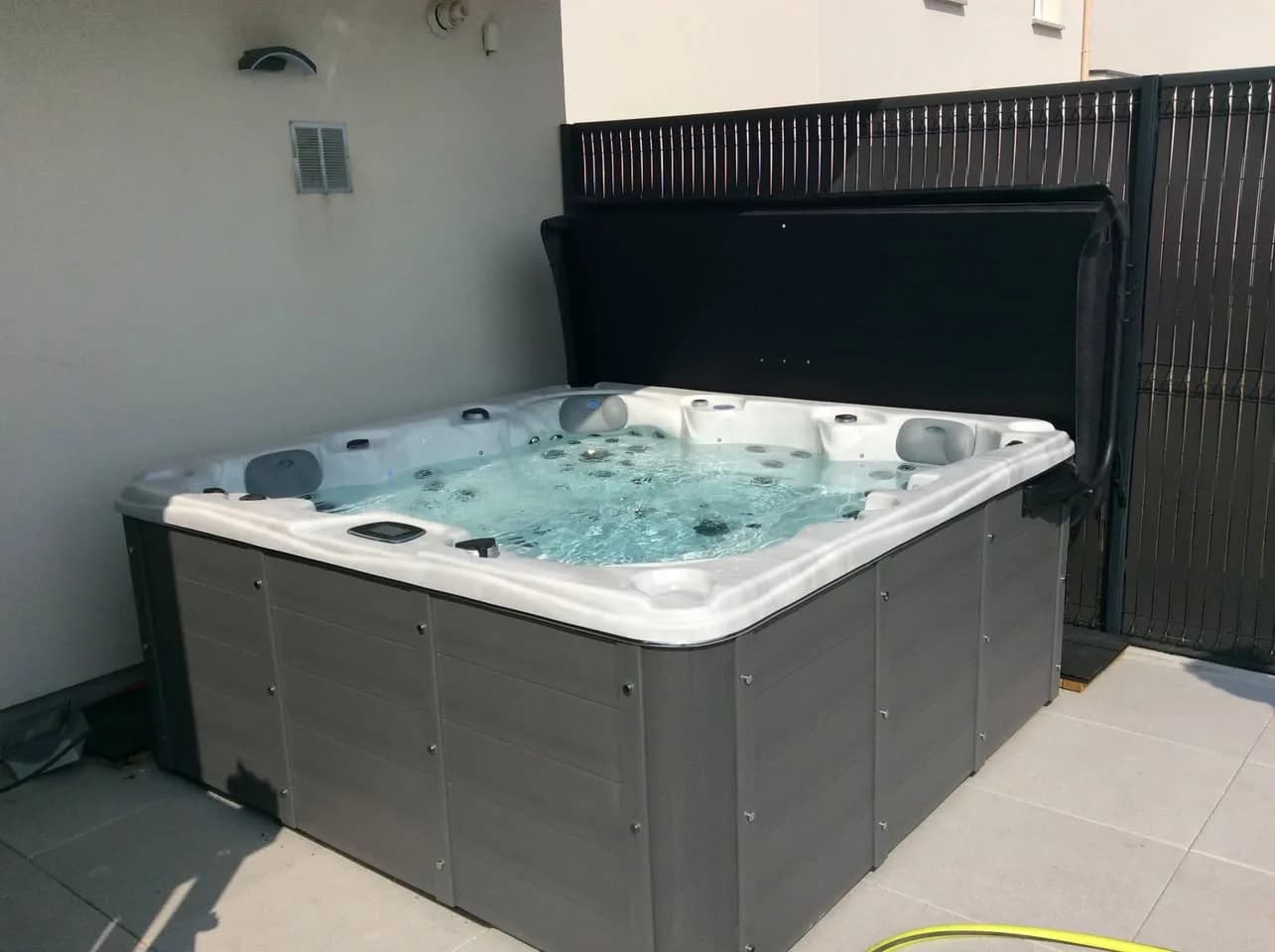 Installation d'un spa Ottawa à Verry, sur une dalle devant une palissade grise