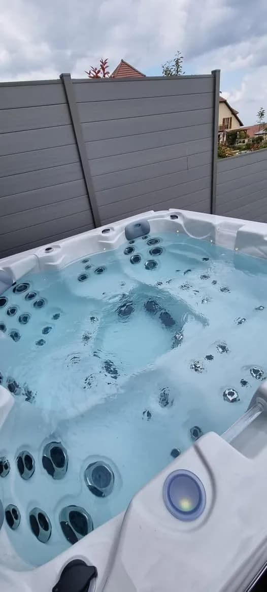 Installation d'un spa Ottawa, sur une terrasse devant une palissade grise