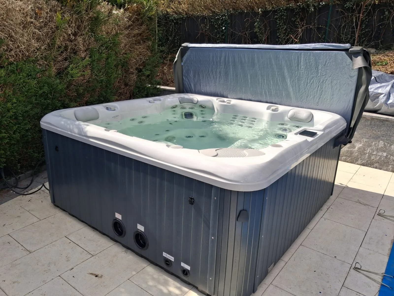 Installation d'un spa Poséidon à Lautenbach-Zell, sur une dalle carrelée devant une haie