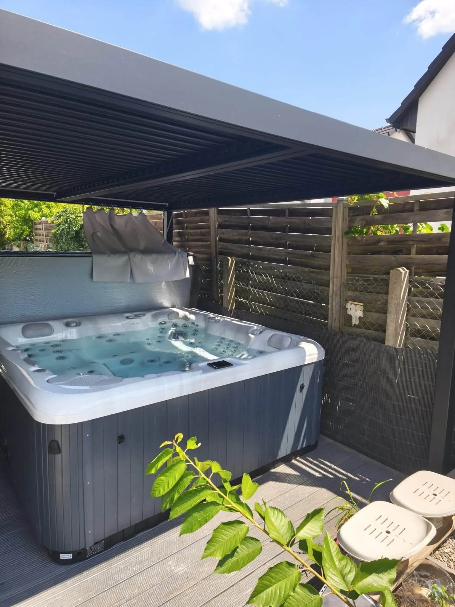 Installation d'un spa Poséidon à Munchhouse, sous une pergola en aluminium, terrasse en lames