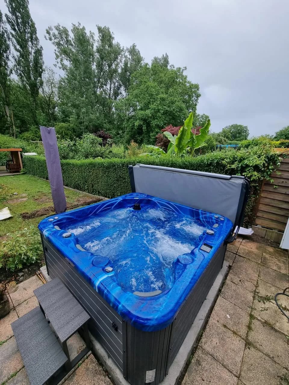 Installation d'un spa Poséidon à Ottmarsheim, cuve bleue dans un jardin arboré
