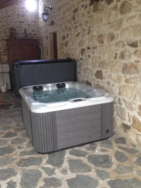 Installation d'un spa Puerla en Ardèche, sur un dallage en pierre, contre un mur en pierre