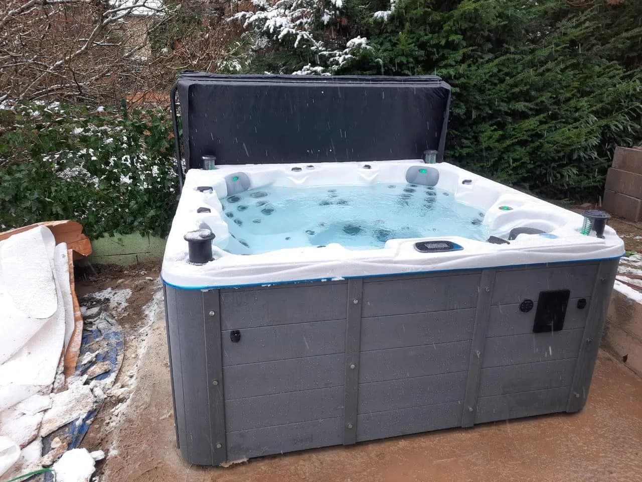 Installation d'un spa Québec Full option à Sausheim, devant une haie, lève-couverture
