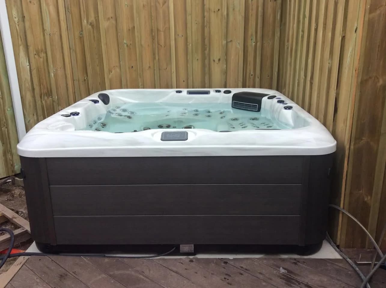 Installation d'un spa RC7 Full option à La Teste-de-Buch, sur une dalle devant une palissade en bois