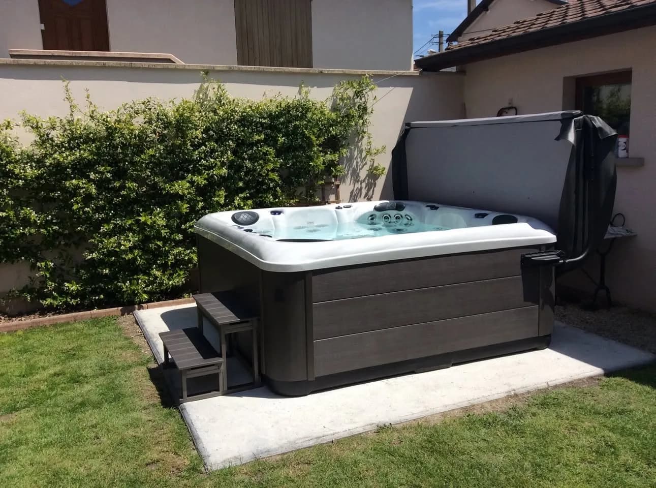 Installation d'un spa RC7 à Villeurbanne, sur une dalle devant une haie