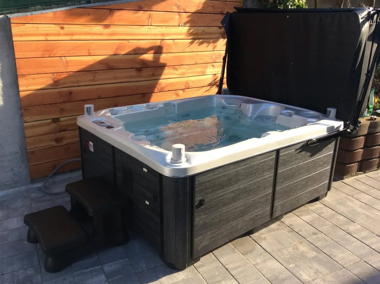 Installation d'un spa Rødberg Full option à Griesbach-au-Val, sur une terrasse dallée devant un bardage en bois