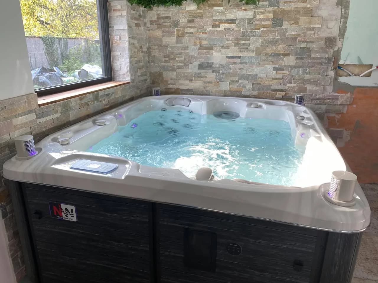 Installation d'un spa Rødberg à Wittisheim, contre un mur en parement de pierre