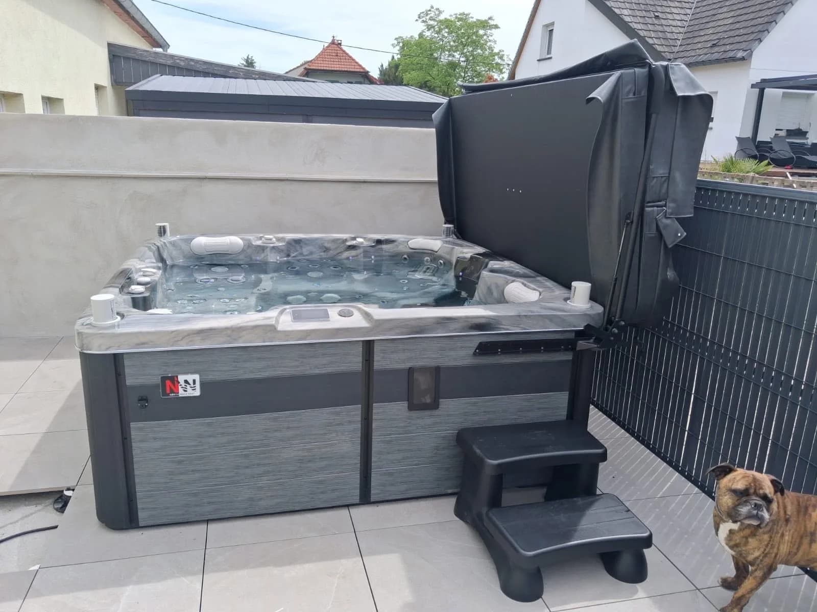 Installation d'un spa Sølveijg Full option à Habsheim, sur une terrasse carrelée contre une clôture occultante